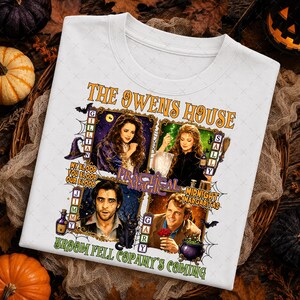 May include: A white t-shirt featuring a graphic print titled The Owens House with four framed portraits of characters from Practical Magic. The design includes text such as My Blood Your Blood Our Blood, Midnight Margaritas, and Broom Fell Copany's Coming.