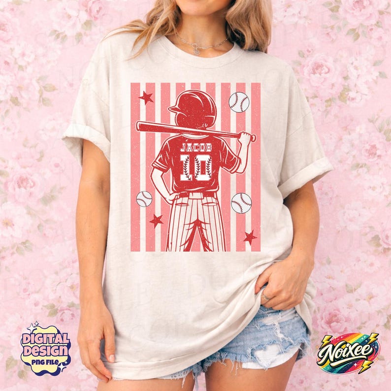 May include: Cream-colored t-shirt featuring a red baseball player graphic with the name "Jacob" and the number "10". The design includes baseballs, stars, and a striped background. The shirt has short sleeves.