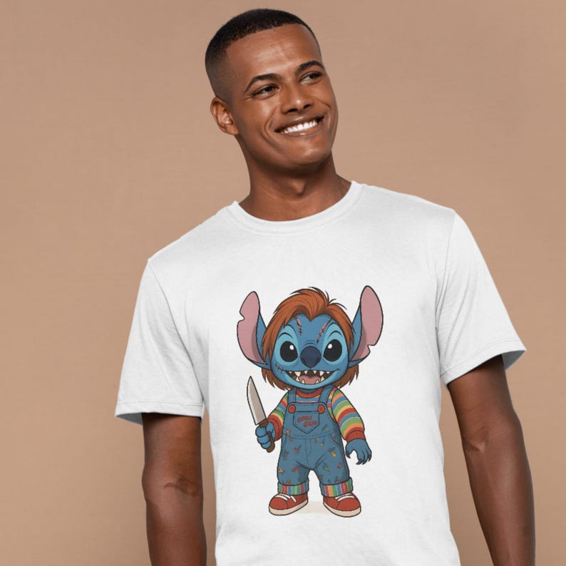 May include: White t-shirt featuring a cartoon character with blue skin, large ears, and orange hair, dressed in blue overalls and holding a knife. The character is a mashup of Stitch and Chucky.