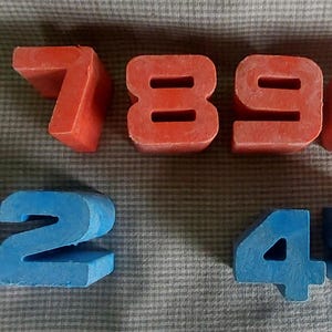May include: A set of red and blue plastic number blocks. The numbers 7, 8, 9, 0, 1, 2, 4, and 5 are visible.