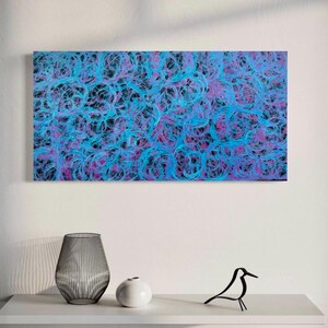 May include: Abstract painting with swirling blue and purple lines on a black background. The painting is framed and hanging on a white wall.