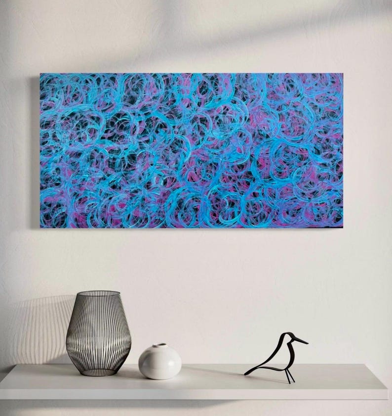 May include: Abstract painting with swirling blue and purple lines on a black background. The painting is framed and hanging on a white wall.