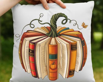 May include: White square pillow with a pumpkin design made of open books. The books are in shades of orange, red, and brown, with a green stem and vines. A fall-themed decorative pillow.