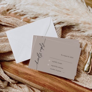 Puede incluir: Una tarjeta RSVP de color marrón claro con el texto "Kindly reply by August 10, 2025". Hay dos casillas de verificación, una para "joyfully accepts" y otra para "regretfully declines". Hay una línea para el número de invitados.