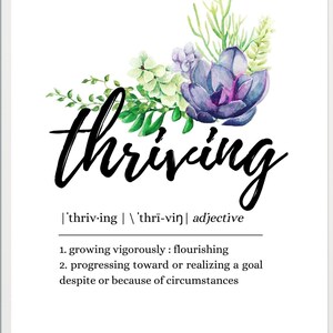 以下が含まれることがあります： 「thriving」という言葉が黒いエレガントな筆記体で書かれた額入りのプリント。緑と紫の色合いの水彩画の花のアレンジメントが添えられています。「thriving」の定義も含まれています。