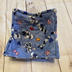 May include: A blue fabric bowl with a Mickey Mouse and Minnie Mouse print. The bowl has a white background with red, yellow, and black accents.