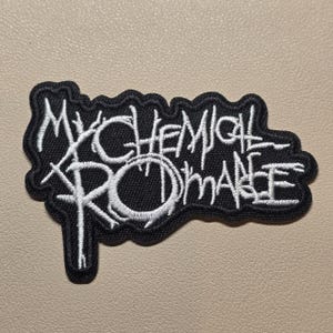 May include: A black embroidered patch featuring the white text My Chemical Romance in a stylised, jagged font. The patch has a thick black border that follows the irregular, organic shape of the lettering, creating a distinct, high-contrast design.