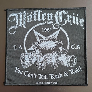 May include: A square black embroidered patch featuring the white text Mötley Crüe at the top, 1981 in the centre, and L.A. C.A. on the sides. A central pentagram graphic surrounds a figure with spiky hair, and the text You Can't Kill Rock & Roll!