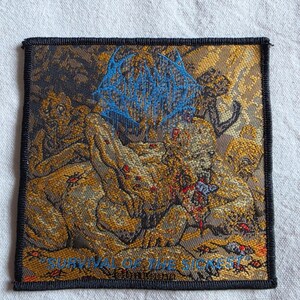 May include: A square embroidered patch with a black border featuring a detailed graphic of a creature in shades of gold, brown, and red. The text "BLOODBATH" appears in blue at the top, and "SURVIVAL OF THE SICKEST" is printed in blue at the bottom.