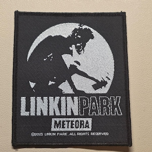 May include: A rectangular black embroidered patch featuring a white circular graphic of a person spray painting. The text LINKIN PARK appears in white, followed by METEORA in a white box, and the copyright text 2025 LINKIN PARK. ALL RIGHTS RESERVED.