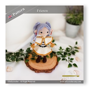 Puede incluir: Una muñeca elfo de crochet con cabello morado, vistiendo un vestido blanco y marrón con un cinturón amarillo. La muñeca está de pie sobre una rodaja de madera.