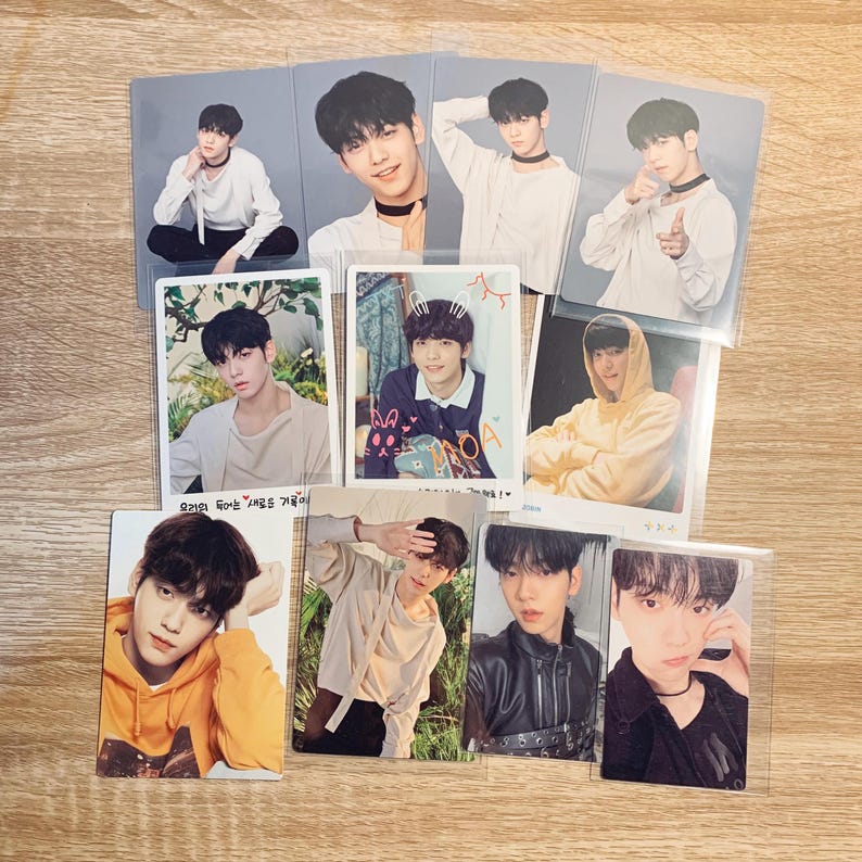 May include: A collection of photo cards featuring a group of young men. The cards are printed on white cardstock and feature various poses and expressions. The cards are all in portrait orientation and have a white border around the image. The text on the cards is in Korean.