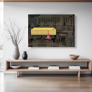 Könnte beinhalten: Ein gerahmter Kunstdruck mit einem gelben Gebäude mit roter Struktur vor einem dunklen Hintergrund von Stadtlandschaften. Das Wort "Mainz" ist in Weiß dargestellt. Das Kunstwerk wird über einer Holzkonsolentisch ausgestellt.
