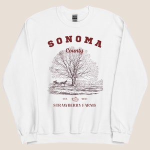 May include: White sweatshirt with a red print of "Sonoma County" and a drawing of a tree and a horse-drawn carriage. The text "EST. 1850 STRAWBERRY FARMS" is printed below the drawing.