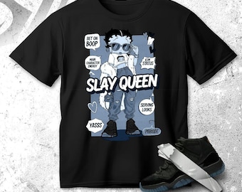 May include: Black t-shirt featuring a cartoon illustration of a character wearing sunglasses and the text "SLAY QUEEN." The design includes speech bubbles with phrases like "BET ON BOOP" and "SERVING LOOKS." A pair of black sneakers with a blue sole are in the foreground.