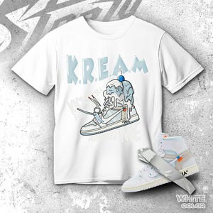 Puede incluir: Camiseta blanca con un gráfico de un helado derritiéndose sobre una zapatilla deportiva, con la palabra "KREAM" encima. Un par de zapatillas deportivas blancas y azul claro también están en la imagen. Las palabras "WHITE COLOR" están en la parte inferior.