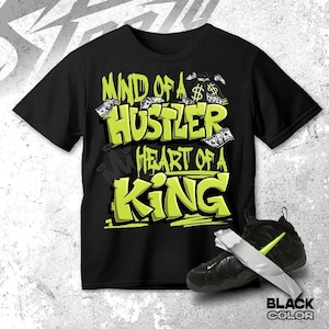 May include: Black t-shirt with the text "MIND OF A HUSTLER HEART OF A KING" in neon green. The design includes money bag graphics and dollar bills. A pair of black sneakers with neon green accents are also in the image.