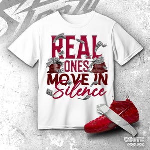 May include: A white short-sleeve t-shirt featuring the dark red text "REAL ONES MOVE IN SILENCE" with graphics of two brown money bags overflowing with cash and floating dollar bills. A red sneaker with a silver strap is positioned at the bottom.
