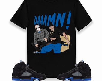 May include: Black t-shirt with a graphic of two men sitting on a couch, one wearing a hockey mask and the other with tattoos. The text "DAAAAMN!" is printed in blue above the graphic. A pair of black and blue Air Jordan 5 Retro sneakers are shown below the t-shirt.