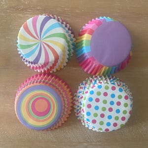 May include: Four colorful cupcake liners with different patterns. The liners are pink, purple, blue, green, orange, and yellow. The patterns include a swirl, polka dots, and concentric circles.
