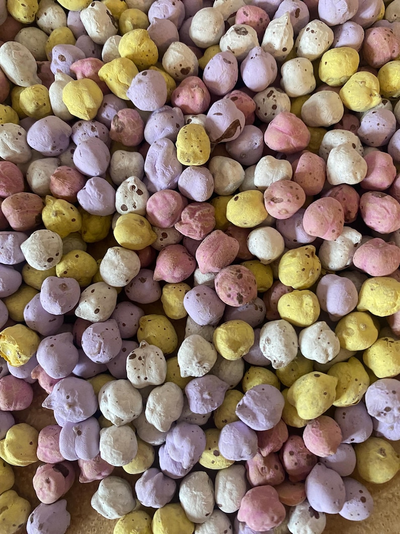 Pu&ograve; includere: Primo piano di una collezione di caramelle rotonde e colorate. Le caramelle sono in vari colori pastello, tra cui giallo, rosa, viola e bianco. Alcune caramelle hanno motivi maculati. Le caramelle sembrano essere un tipo di confetteria.