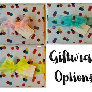 May include: Three gift boxes wrapped in white paper with a confetti pattern of colorful circles. Each box is tied with a different colored sheer ribbon: pink, teal, and yellow. The boxes are arranged in a grid pattern with the text "Giftwrap Options" below.