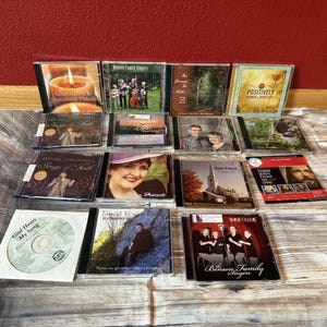 May include: A collection of CDs featuring various artists and musical themes. The CDs are in clear plastic cases, with colorful cover art. Some covers feature images of people, while others display landscapes or text.