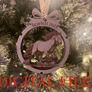 Könnte beinhalten: Weihnachtsbaumschmuck aus Holz mit einem galoppierenden Pferd. Der runde Schmuck trägt den Namen "Scarlett" und das Jahr "2025". Er hängt an einem Band. Die Worte "DIGITAL FILE ONLY .SVG" sind rot gedruckt.