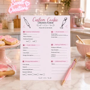 May include: A pink custom cookie order form with text fields for customer and event details. A pink pen with a glittery barrel rests on the form. The background includes a pink stand with cookies and a neon sign.