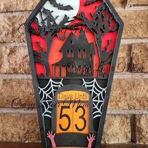 May include: Black wooden Halloween countdown sign shaped like a coffin with a haunted house, bats, and a full moon. The sign says "Days Until Halloween" and shows the number "53".