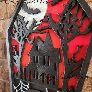 May include: A wooden Halloween countdown plaque with a black silhouette of a haunted house, trees, bats, and a moon. The plaque has a white spider web and the text "Days Until" on a black tombstone.