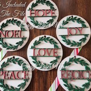 Könnte beinhalten: Weihnachtsschmuck aus Holz mit den Wörtern "HOPE", "NOEL", "JOY", "LOVE", "PEACE" und "REJOICE" in Rot. Jeder Schmuck hat ein grünes Kranzdesign. Der Text "All 6 Included In The File" ist ebenfalls sichtbar.