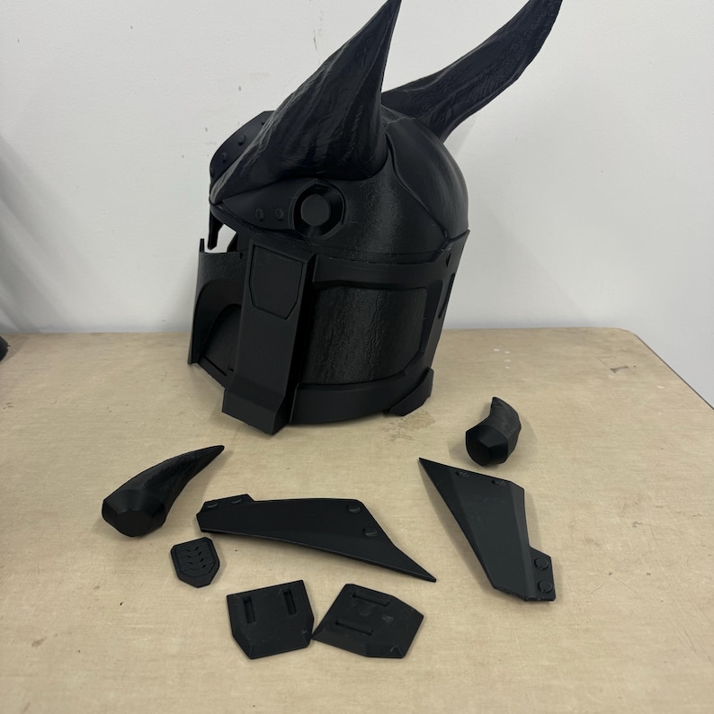 Puede incluir: Un casco negro impreso en 3D con cuernos y varias piezas desmontables. El casco est&aacute; hecho de un material pl&aacute;stico texturizado.