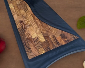 May include: A black and brown wooden cutting board with a unique wave design. The board has a smooth, black surface and a textured, brown surface. The board is perfect for serving cheese, charcuterie, or other appetizers.