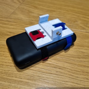 May include: A white 3D printed phone mount with a red and blue strap. The mount has a hole for a screw and is attached to a black phone case.