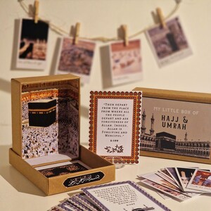 May include: A small box with a brown exterior and a picture of the Kaaba on the front. The box contains a set of cards with Islamic quotes and images related to Hajj and Umrah. The box is labeled "My Little Box of Hajj & Umrah".