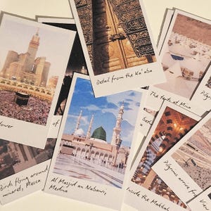 May include: A collection of Polaroid photos of the Kaaba in Mecca, Saudi Arabia. The photos show the Kaaba from different angles, including a close-up of the door, the surrounding area, and the mosque. The photos are labeled with handwritten captions, such as "Detail from the Ka'aba", "The tents at Mina", and "Pilgrims arrive for View".