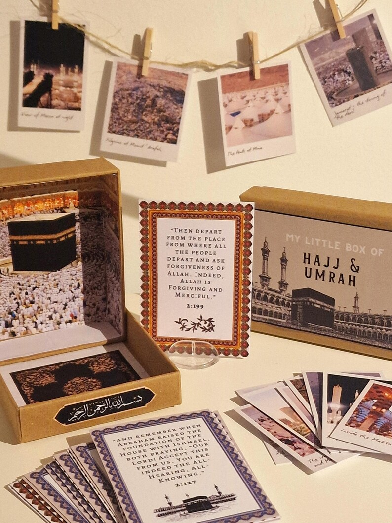 May include: A brown box with a gold lid and a small white card with text that reads "Then depart from the place from where all the people depart and ask for forgiveness of Allah. Indeed, Allah is forgiving and merciful. 2:199". The box is labeled "My Little Box of Hajj & Umrah". The box contains a set of small cards with images and text about the Hajj and Umrah pilgrimages.