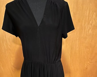 May include: A black short-sleeved dress with a v-neck and a gathered waist.
