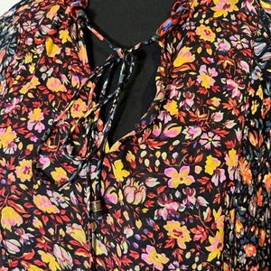 May include: A black dress with a floral print in shades of red, yellow, pink, and blue. The dress has a V-neckline and a tie at the front.