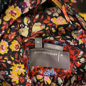 May include: A black and red floral print top with a grey tag that reads "ANTHROPOLOGIE" and "XS" in white text. The tag also says "Made in Indonesia" and "Lingerie and Sleepwear".