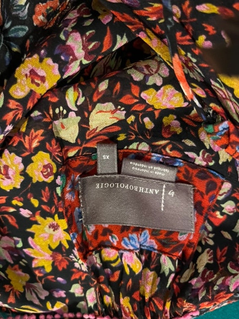 May include: A black and red floral print top with a grey tag that reads "ANTHROPOLOGIE" and "XS" in white text. The tag also says "Made in Indonesia" and "Lingerie and Sleepwear".