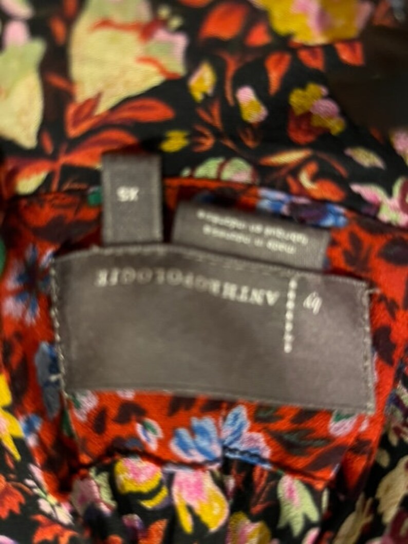 May include: A black and red floral print fabric with a grey tag that reads "ANTHROPOLOGIE" and "XS".