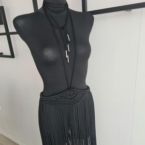 Black long macramé skirt connected to a neck accessory with metallic details, showcasing intricate handmade patterns and a bold, elegant design, perfect for special occasions or festivals.