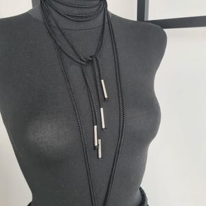 Close-up of a neck accessory made from macramé cords with metallic details, highlighting the intricate handmade design and bold, unique style.