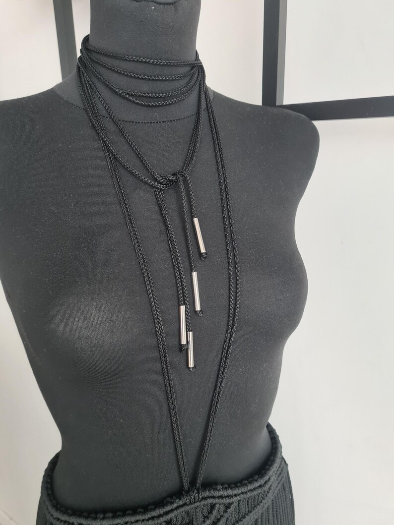 Close-up of a neck accessory made from macramé cords with metallic details, highlighting the intricate handmade design and bold, unique style.