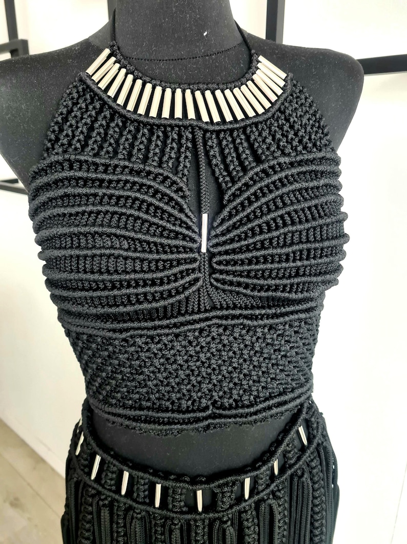 Black luxurious macramé top with metallic details, worn by a model, perfect for festivals, parties, or the beach, showcasing intricate handmade craftsmanship and a stylish, bold design.