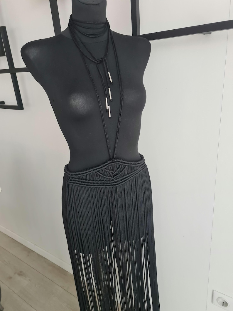 Black long macramé skirt connected to a neck accessory with metallic details, showcasing intricate handmade patterns and a bold, elegant design, perfect for special occasions or festivals.