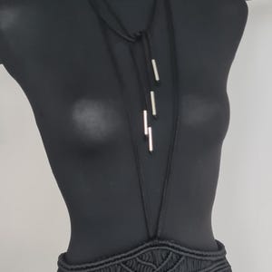 Close-up of a neck accessory made from macramé cords with metallic details, highlighting the intricate handmade design and bold, unique style.