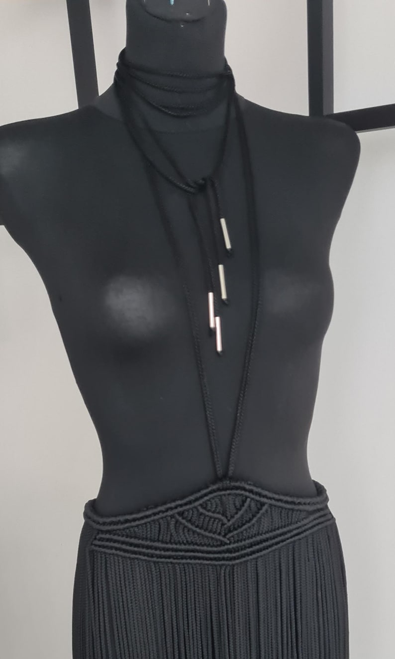 Close-up of a neck accessory made from macramé cords with metallic details, highlighting the intricate handmade design and bold, unique style.